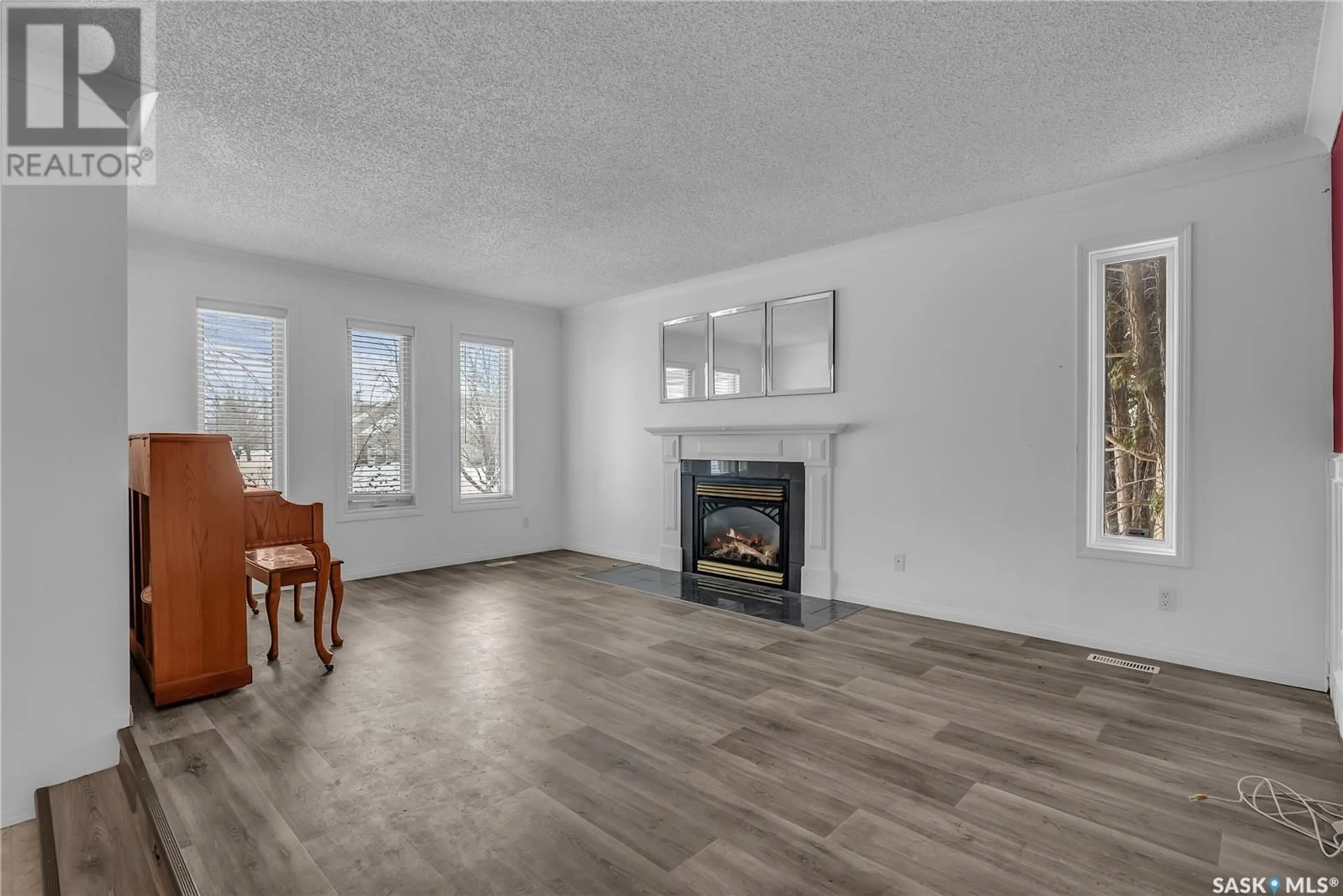 Living room with furniture, wood/laminate floor for 122 Mulcaster CRESCENT, Saskatoon Saskatchewan S7N4A7