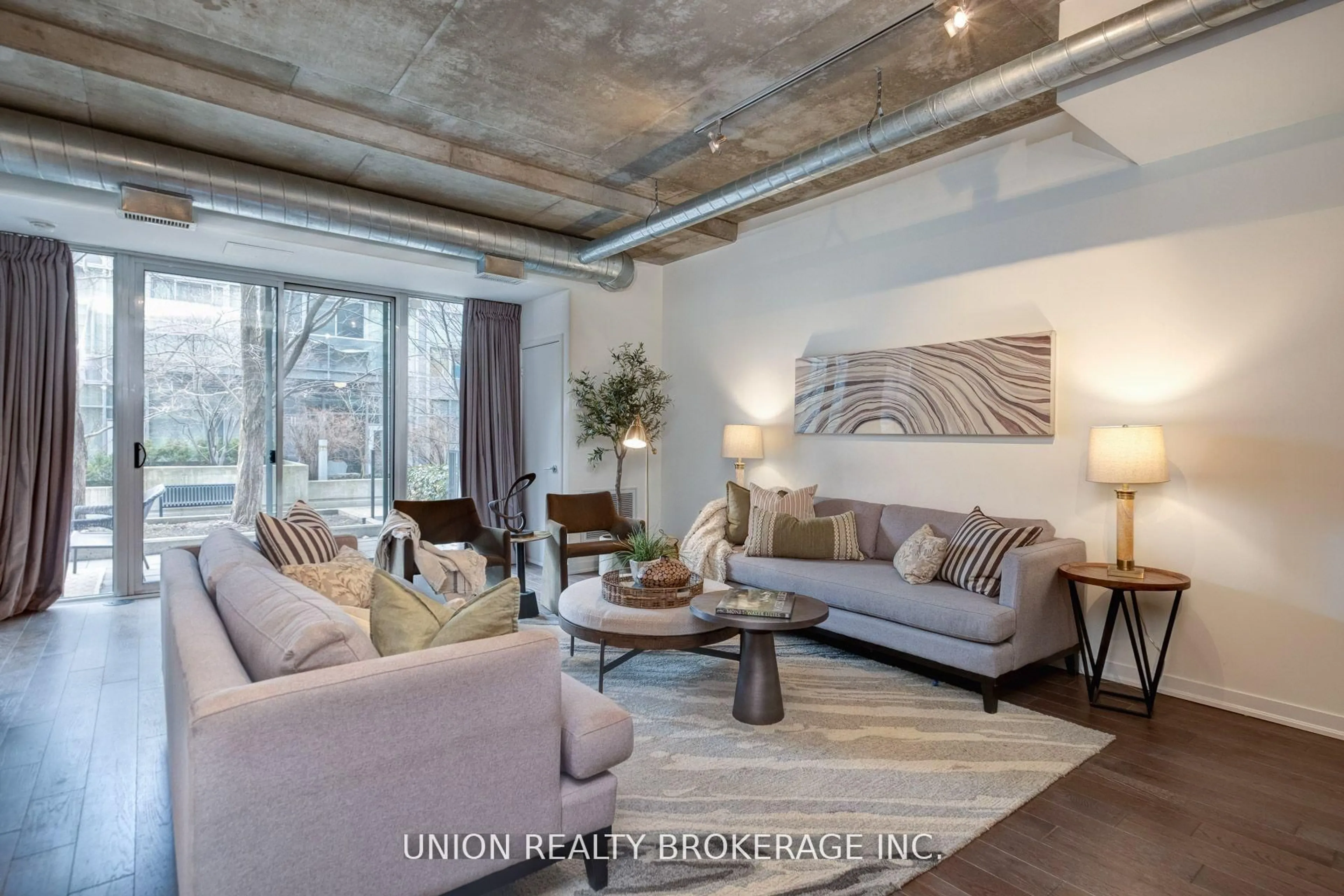 Living room with furniture, cement floor for 201 Carlaw Ave #105, Toronto Ontario M4M 2S3