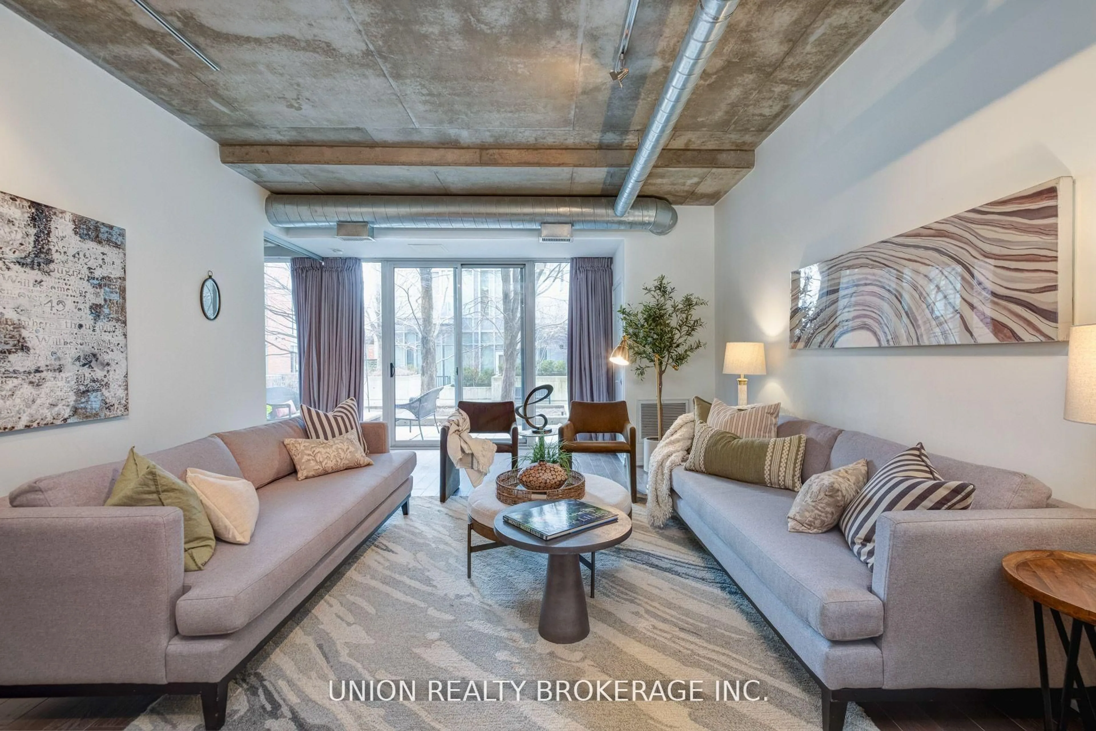 Living room with furniture, cement floor for 201 Carlaw Ave #105, Toronto Ontario M4M 2S3