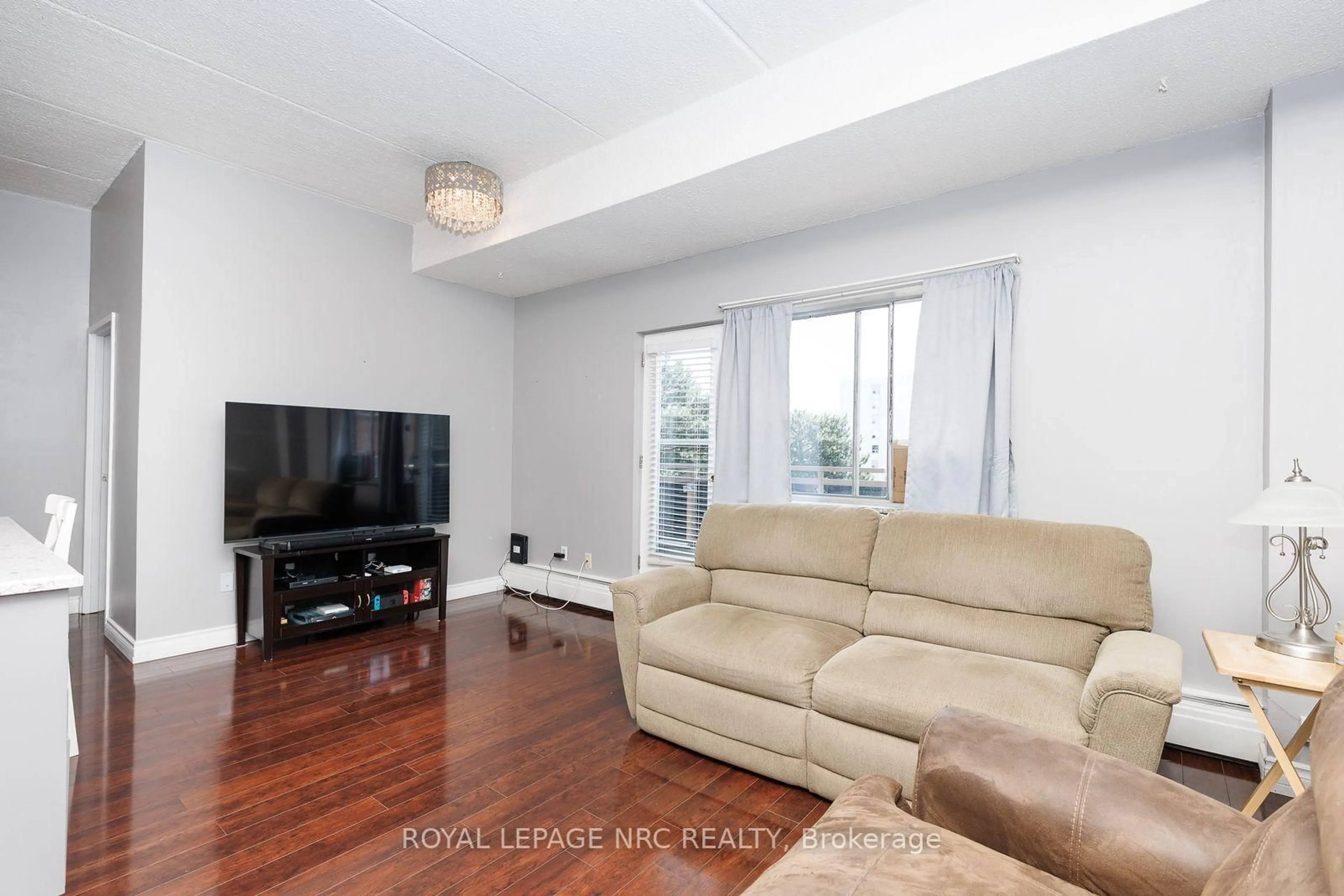 Living room with furniture, wood/laminate floor for 196 Scott St #515, St. Catharines Ontario L2N 5T2